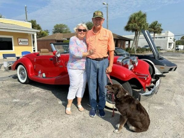 preston and sherrill with their dog in front of classic cars